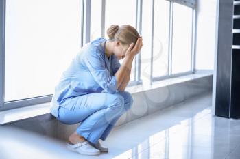 Depressed medical assistant near window in clinic�