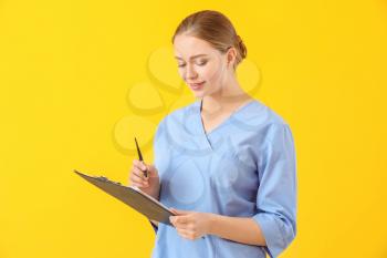 Young medical assistant with documents on color background�