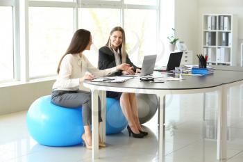 Young businesswomen sitting on fitballs while working in office�