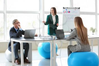 Young business people sitting on fitballs while working in office�