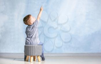 Little boy with autistic disorder sitting near light wall�