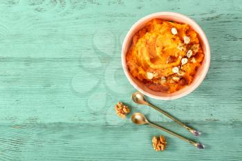Bowl with mashed sweet potato and nuts on wooden background�