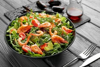 Plate with tasty shrimp salad on table�