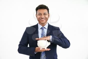 Handsome businessman with piggy bank on white background�