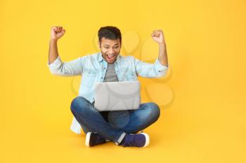 Happy man with laptop on color background�