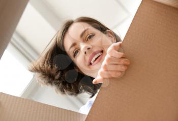 Young woman opening parcel at home, view from inside of box�