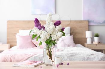 Vase with beautiful lilac flowers on table in bedroom�