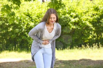 Young woman suffering from abdominal pain outdoors�
