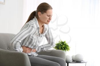 Young woman suffering from abdominal pain at home�