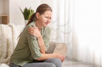 Young woman suffering from pain in shoulder at home�