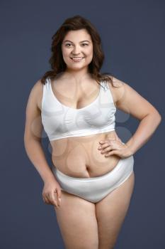Beautiful plus size woman on grey background. Concept of body positive 