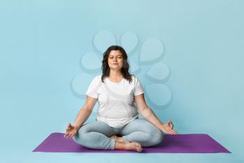 Beautiful plus size woman meditating on color background. Concept of body positive�