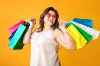 Happy plus size woman with shopping bags on color background�
