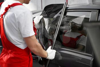 Male worker tinting car window outdoors�