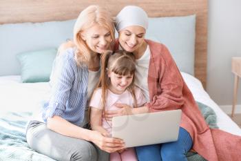 Woman after chemotherapy and her family with laptop at home�
