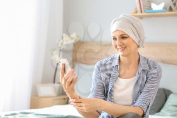 Mature woman after chemotherapy with mobile phone at home�
