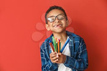 Cute African-American boy with pencils and markers on color background�