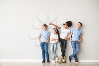 Stylish children in jeans near light wall�