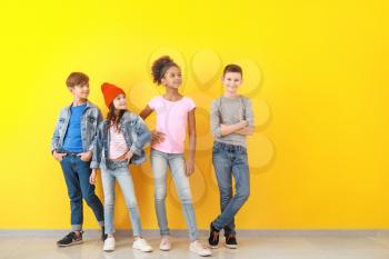Stylish children in jeans near color wall�