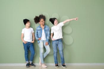Stylish children in jeans clothes near color wall�