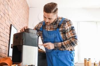 Man repairing coffee machine in kitchen�