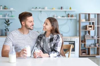 Young couple drinking tasty milk in kitchen at home�