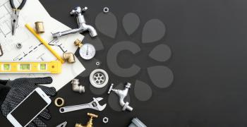 Mobile phone with plumbing items on dark background�