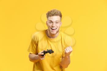 Portrait of happy young man playing video games on color background�