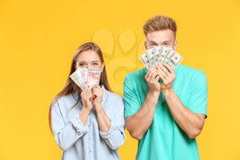 Young couple with money on color background�