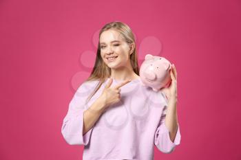 Happy woman with piggy bank on color background�