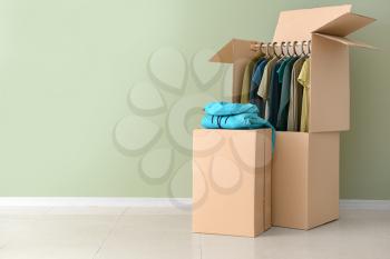 Wardrobe boxes with clothes near color wall�