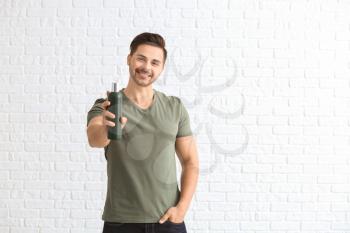 Handsome man with bottle of shampoo on white background�