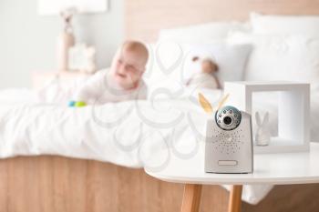 Modern baby monitor on table in room with little child�