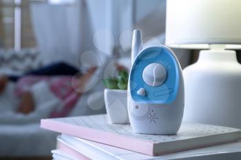 Modern baby monitor on table in child's room late in evening�