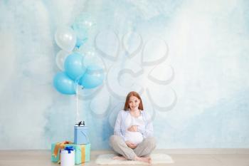 Beautiful pregnant woman with baby shower gifts near color wall�