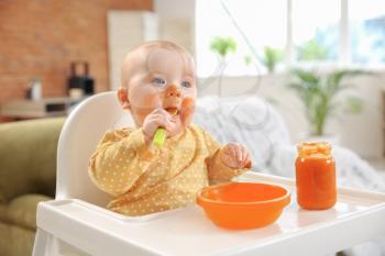 Cute little baby eating tasty food at home�