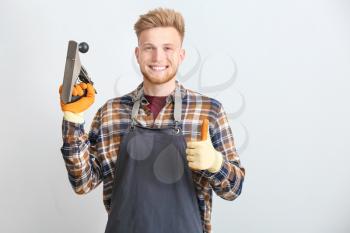 Male carpenter showing thumb-up gesture on grey background�
