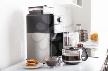 Modern coffee machine and hot beverage on kitchen table�