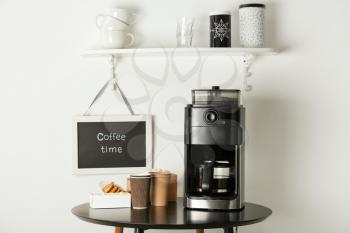 Modern coffee machine, cups and sweets on kitchen table�