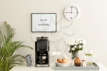 Modern coffee machine, sweets and flowers on kitchen table�