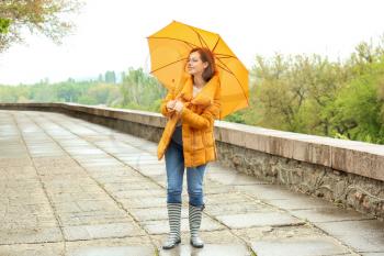 Beautiful young woman with umbrella outdoors on rainy day�
