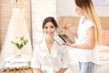 Professional makeup artist working with young bride at home�