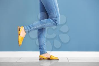 Young woman in stylish shoes against color wall�