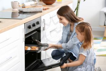 Young woman and her little daughter baking tasty cookies at home�