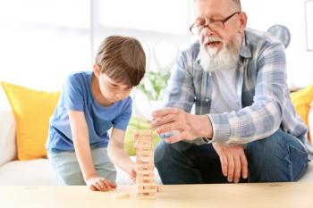 Cute little boy playing with grandfather at home�