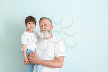 Cute little boy with grandfather on light background�