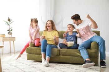 Happy family watching sports on TV at home�