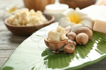 Bowl with shea butter, nuts and flower on plate�