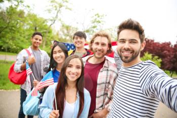 Group of students with USA flag taking selfie outdoors�