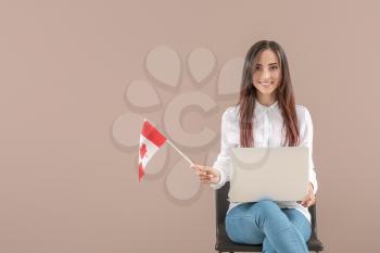 Young student with Canadian flag and laptop on color background�